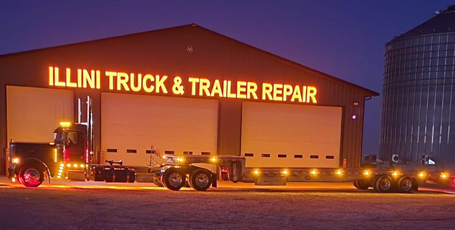 Illini Truck & Trailer Repair shop lit up at dusk with a semi parked out front